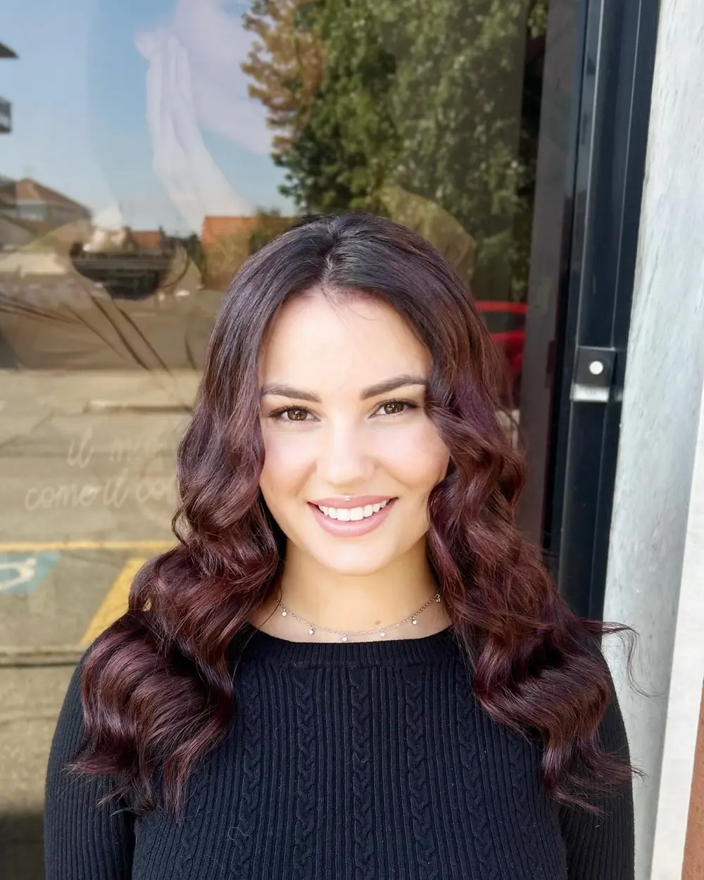 Cliente sorridente con colore rosso ciliegia e piega a onde, realizzati da Salone Solange